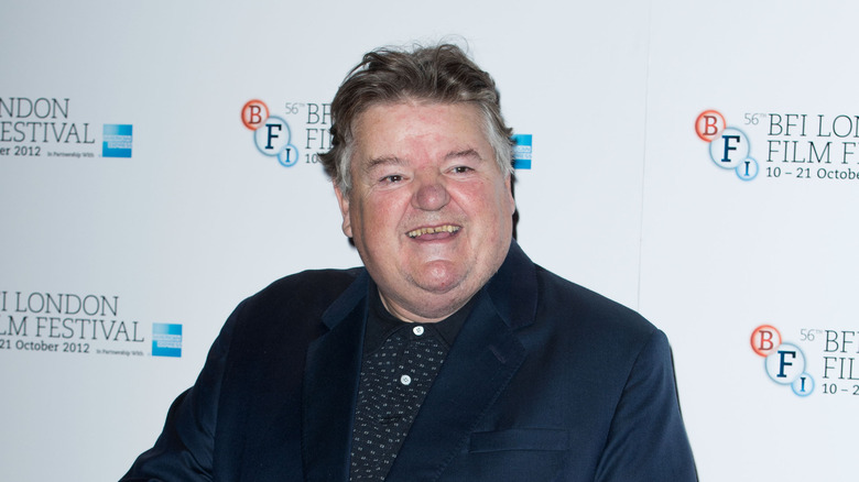 Robbie Coltrane laughing wearing black coat