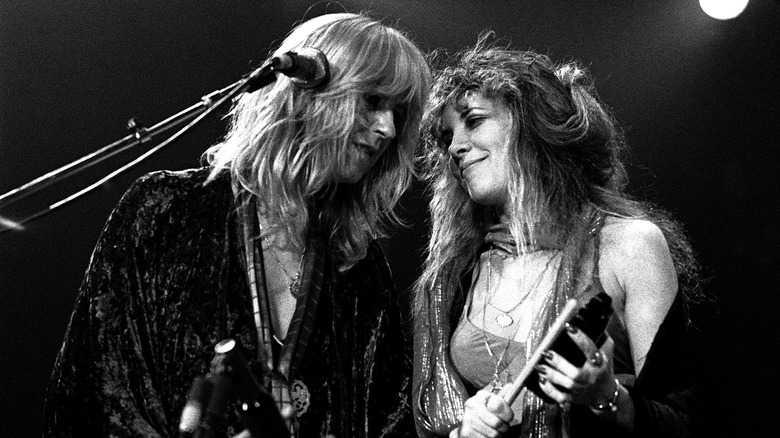 Stevie Nicks smiles at Christine McVie while the two perform on stage.