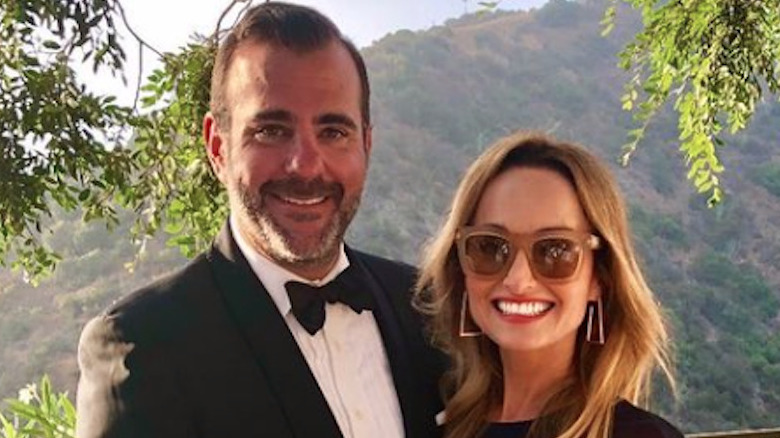 Shane Farley smiles in a tuxedo with Giada De Laurentiis in sunglasses.