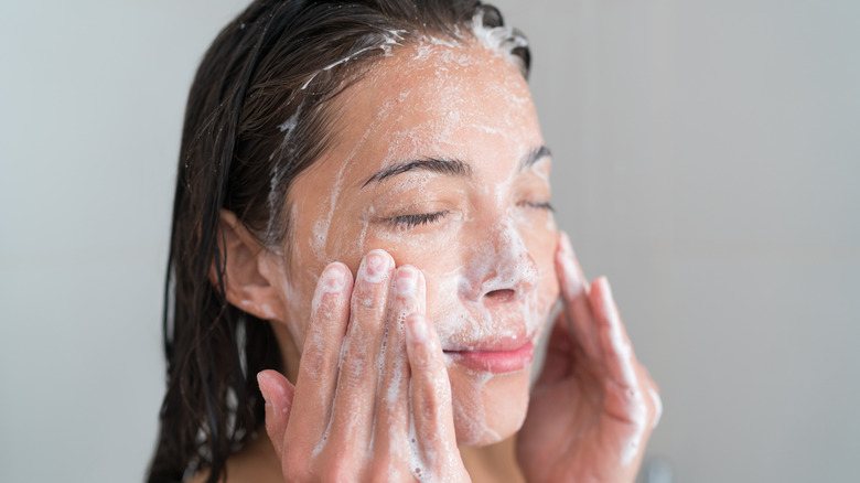 woman cleansing face in shower