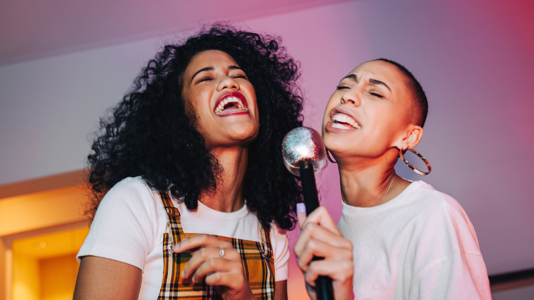 Two women singing into a mic