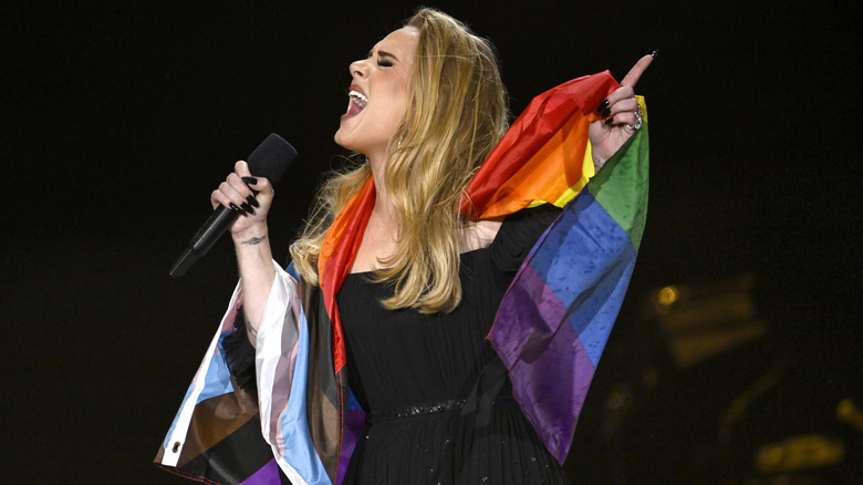 Adele singing into microphone, wrapped in pride flag