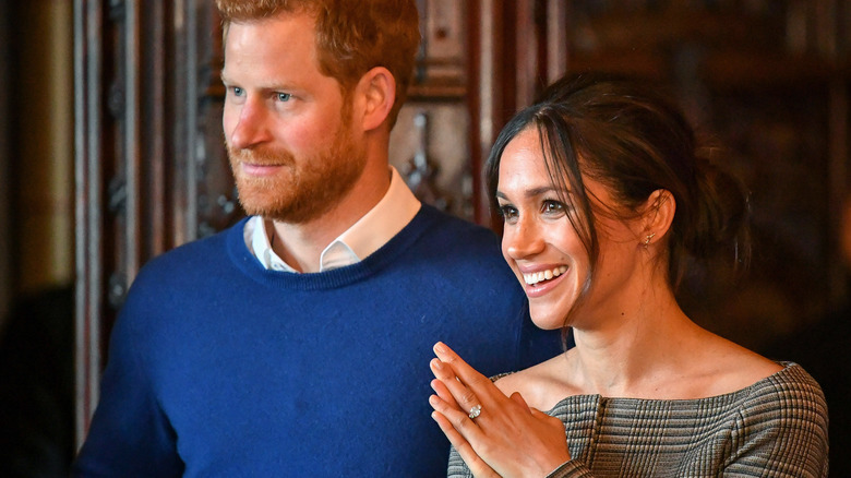 Prince Harry and Meghan Markle listening to someone at an event