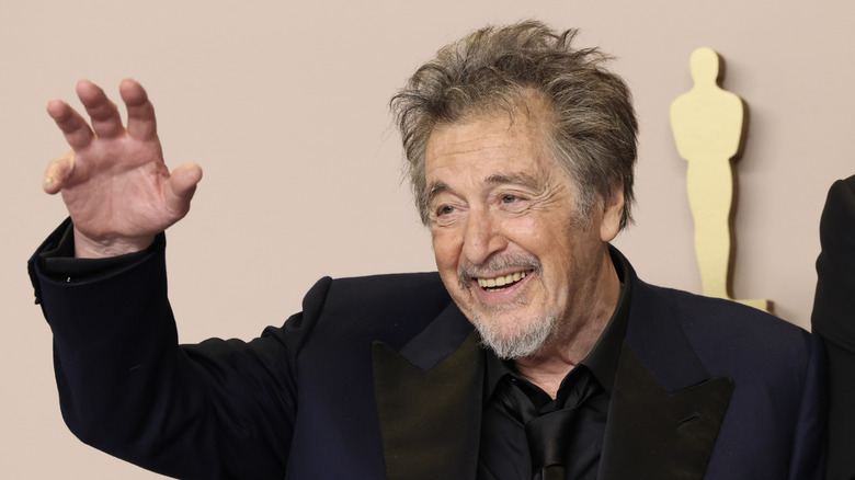 Al Pacino waving in a dark jacket