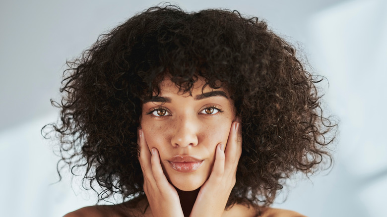 Woman touching face and smiling