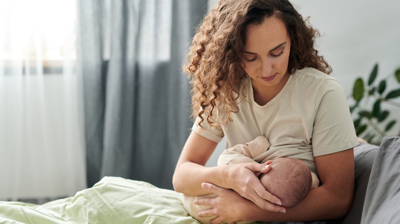 A mom breastfeeding her baby on her bed