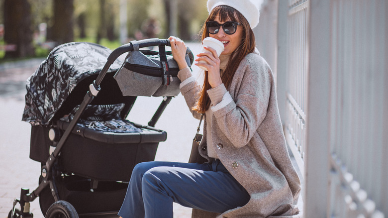 woman drinking coffee pushing stroller