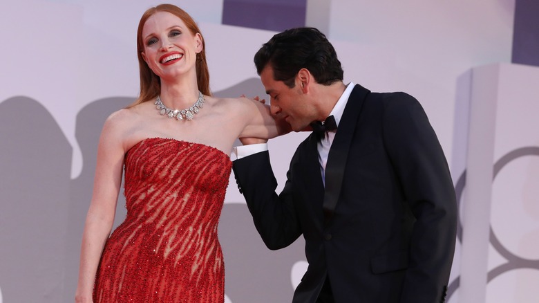 Jessica Chastain smiles while Oscar Isaac kisses the inside of her arm