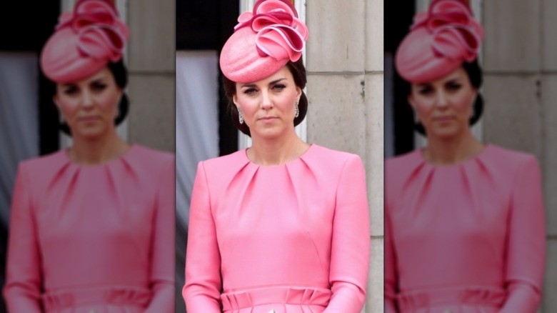 Princess Catherine frowning in pink dress and hat