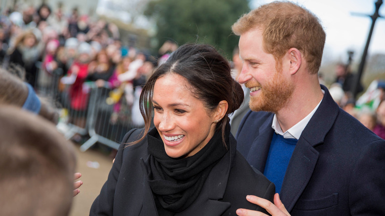 Meghan Markle and Prince Harry smiling to crowds