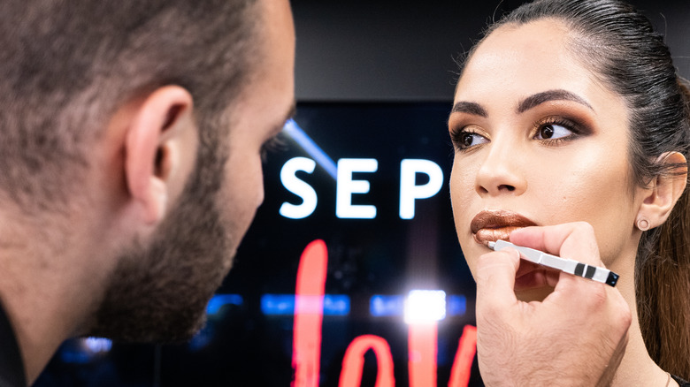 Makeup artist applying lipstick on model at Sephora