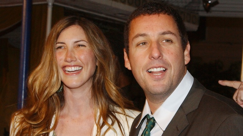 Jackie and Adam Sandler smiling at an event