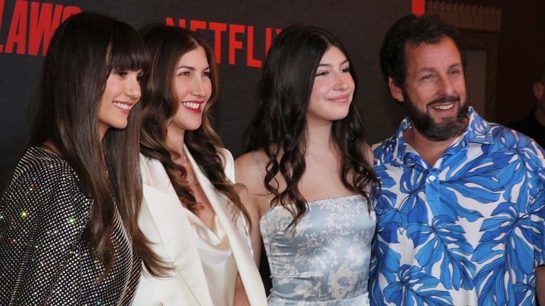 Jackie and Adam Sandler posing with their daughters on a Netflix red carpet