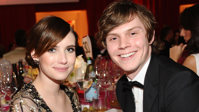 Evan Peters and Emma Roberts sitting at a table