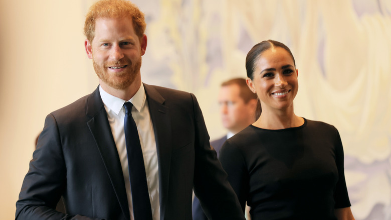 Prince Harry and Meghan Markle smiling and walking