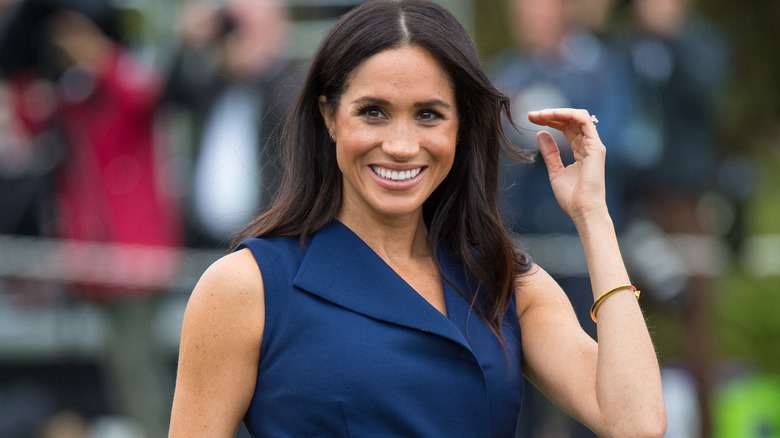 Meghan Markle smiling in navy dress