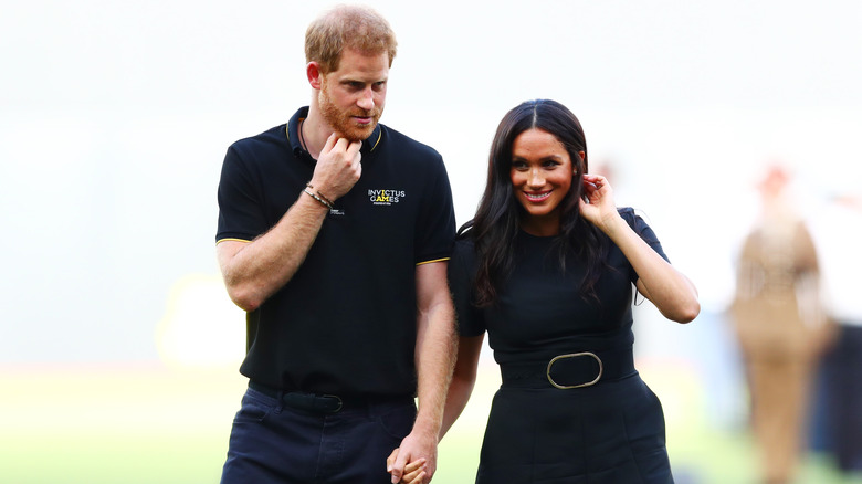 Prince Harry and Meghan Markle holding hands walking