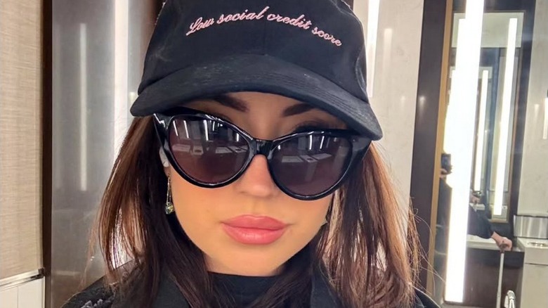 Ashley St. Clair takes a selfie in a hat that says "low social credit score"