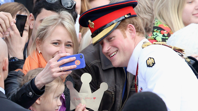 Prince Harry taking a selfie with a fan