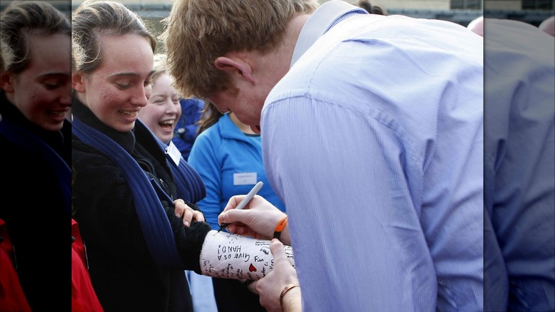 Prince Harry signing a fan's cast