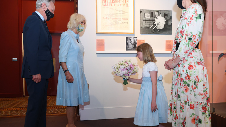 Young girl curtsying to Prince Charles and Princess Camilla