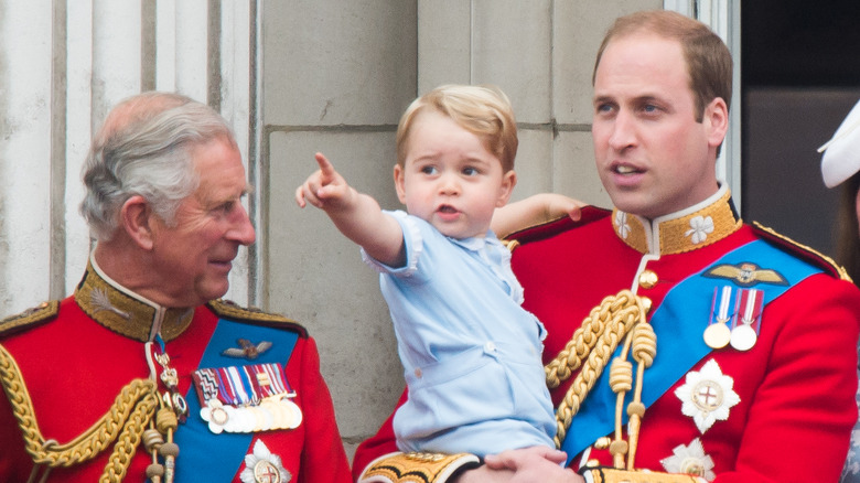 Prince George smiling between King Charles and Prince William