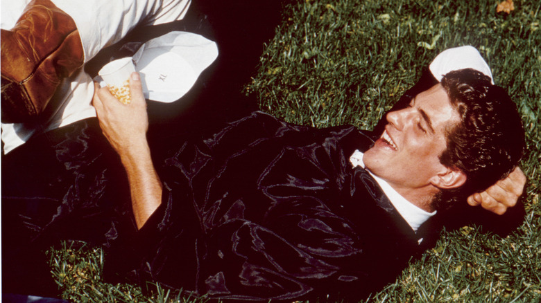 JFK Jr. laying in gass, smiling