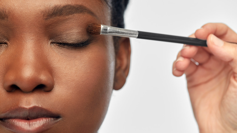 Woman getting eyeshadow applied by a makeup artist