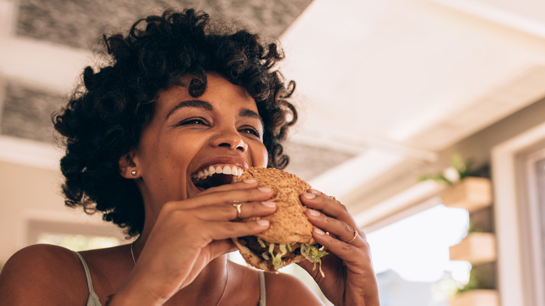 A woman joyously eating a burger