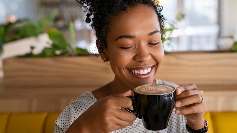 woman smiling while drinking latte