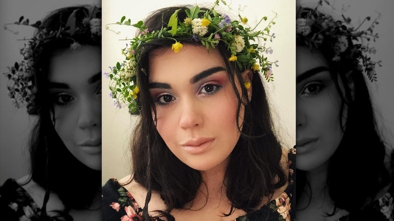 Amber Rachdi with dark hair and flower wreath