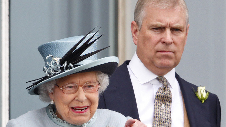 Queen Elizabeth pointing and Prince Andrew looking unhappy