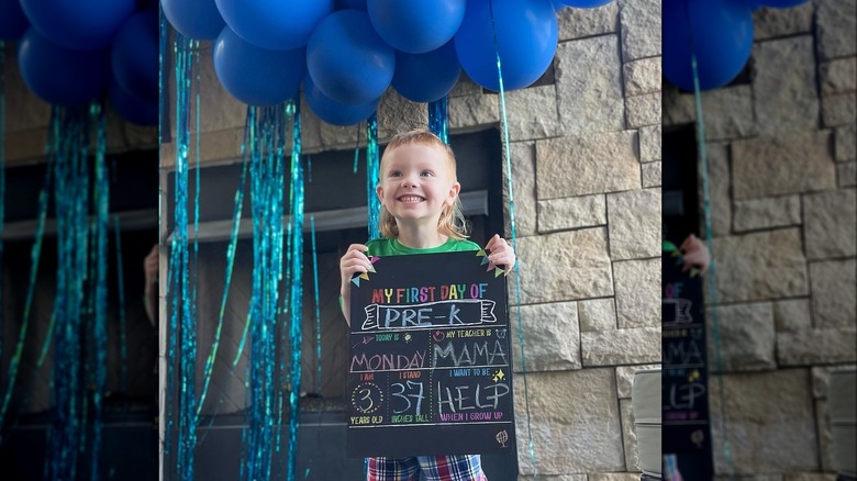 Daxton King holding First Day of School board