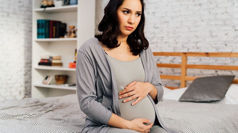 Concerned pregnant mom on a bed