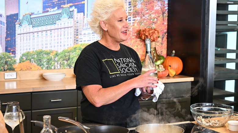 Anne Burrell holding bottle of wine in kitchen