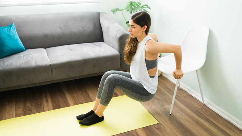 Woman performing tricep dips using chair