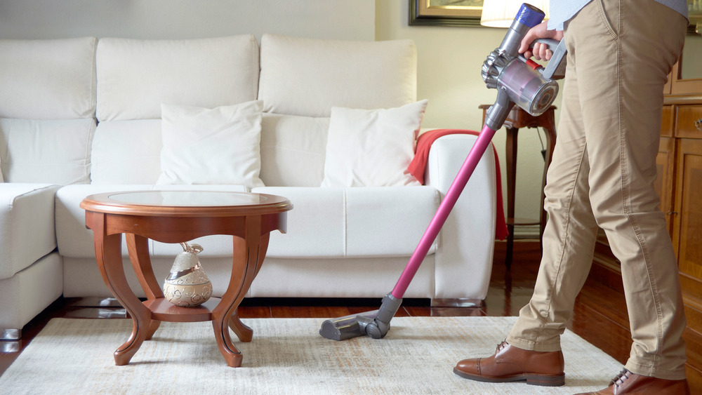 A man holding a cordless vacuum in the living room