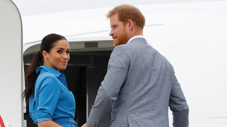 Prince Harry and Meghan Markle board an airplane. 