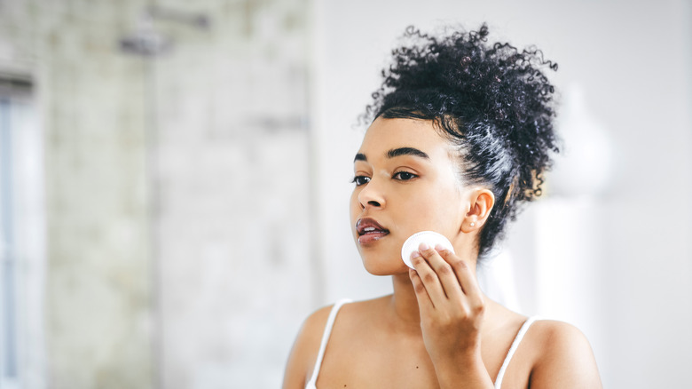 Woman using cotton pad on face