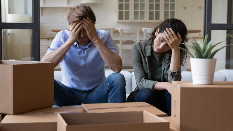 Couple with hands in head and packing boxes