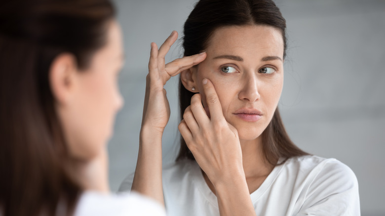 Young woman examining her face in a mirror