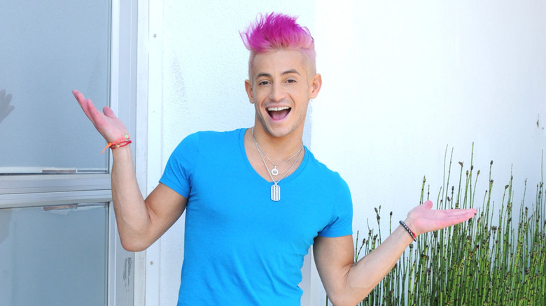 Frankie Grande with pink hair posing outside in front of a window in 2014