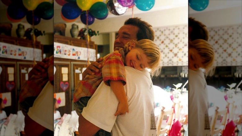 Arnold Schwarzenegger holding young Patrick Schwarzenegger at home