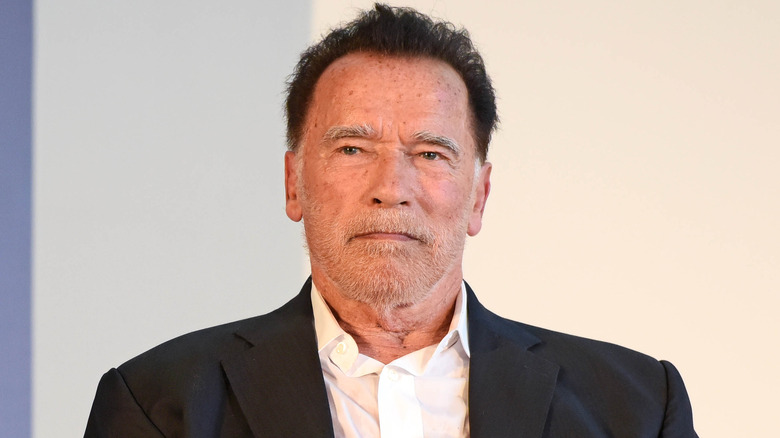 Arnold Schwarzenegger looking stern in a dark suit