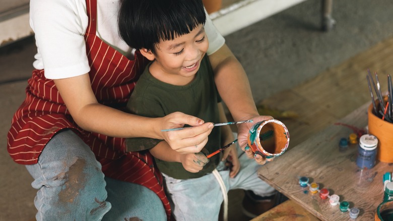 Boy paints clay pot