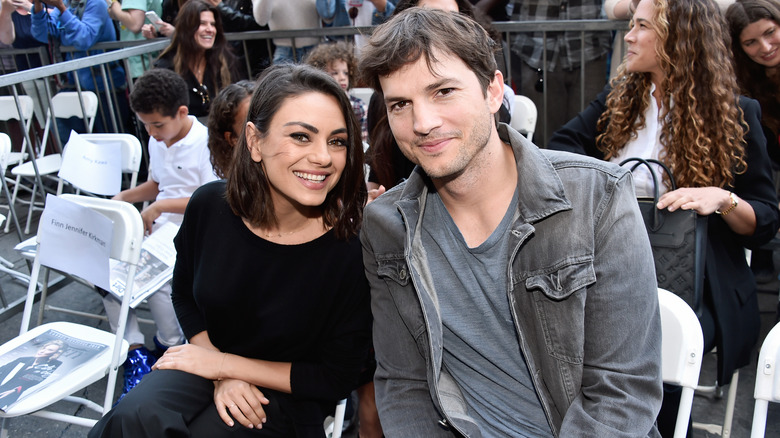 Mila Kunis and Ashton Kutcher sitting in folding chairs