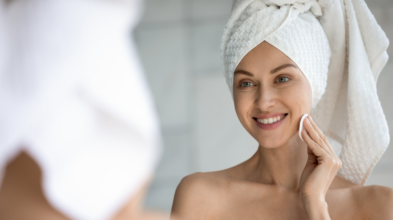 A smiling woman with a cotton pad on her face 