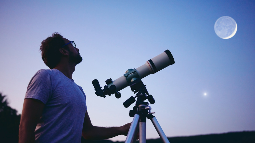 Man with telescope and moon in the background