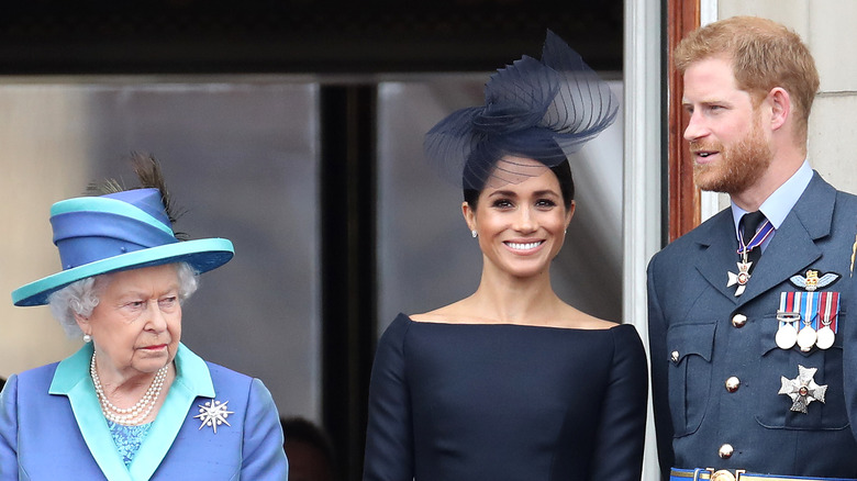 Queen Elizabeth II looks grumpy while Meghan Markle and Prince Harry smile