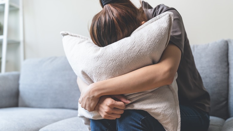 Woman stuffing face into pillow